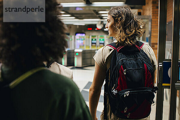 Rückansicht von männlichen und weiblichen Studenten  die an einer U-Bahn-Station gehen
