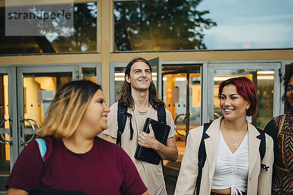 Lächelnd männlichen und weiblichen Studenten im Gespräch mit einander in der Universität Campus