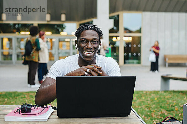 Porträt des männlichen Studenten lachend mit Laptop in College-Campus