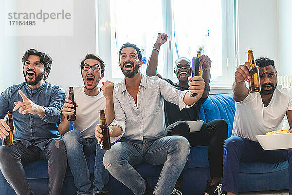 Männliche Freunde trinken Bier und schauen Sport im Fernsehen  jubeln