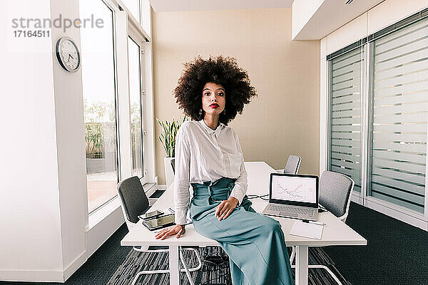 Porträt einer Geschäftsfrau  die auf einem Schreibtisch im Büro sitzt