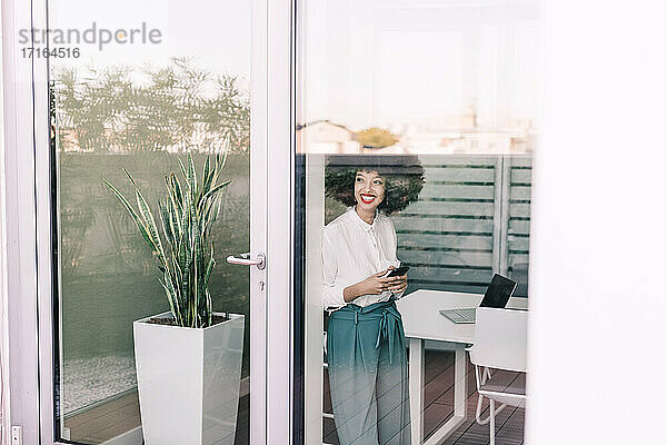 Geschäftsfrau  lächelnd  schaut durch ein Fenster