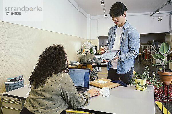 Mann zeigt einem Kollegen im Büro ein digitales Tablet