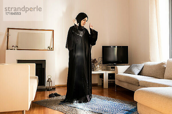Junge muslimische Frau  stehend mit erhobenen Händen beim Gebet