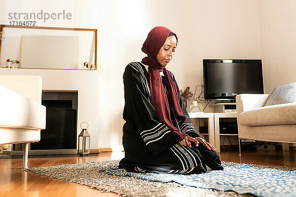 Junge muslimische Frau  kniend beim Gebet