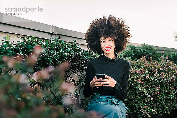 Glückliche junge Frau im Freien mit Mobiltelefon