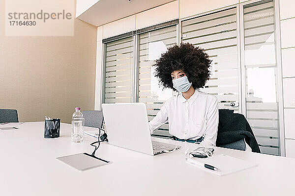 Geschäftsfrau mit Gesichtsmaske bei der Arbeit