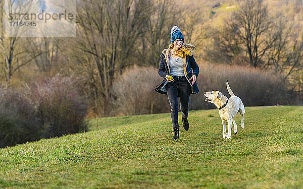 Young woman with dog running in nature