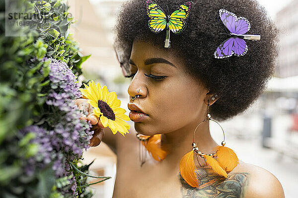 Young Afro woman smelling flower outdoors