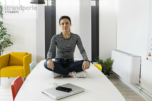 Junge Geschäftsfrau sitzt am Tablet am Arbeitsplatz