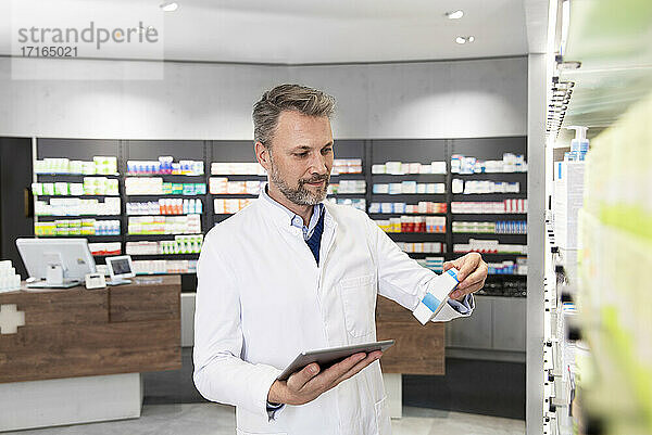 Male pharmacist with digital tablet doing inventory
