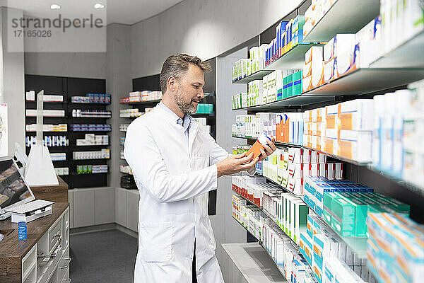 Male pharmacist reading instructions of medicine in store