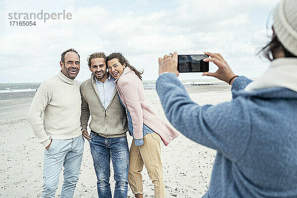 Eine Gruppe von Freunden macht Smartphone-Fotos am Strand