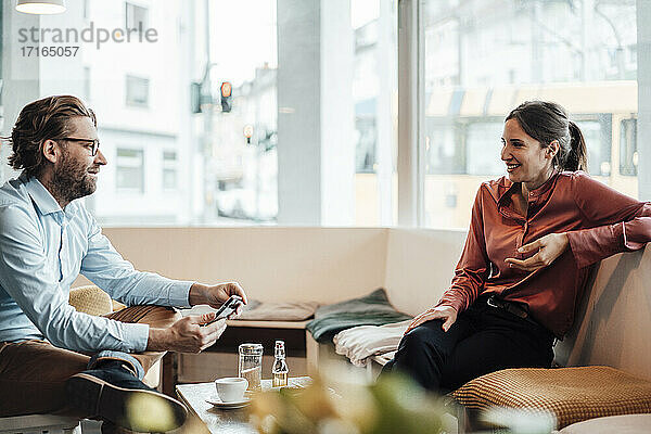Männlicher Unternehmer im Gespräch mit einer Kollegin in einem Café