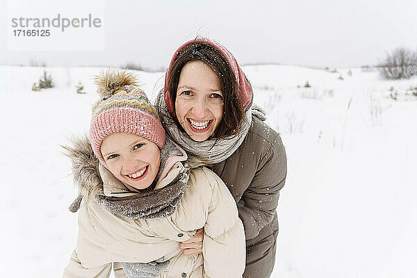 Lächelnde Mutter mit Tochter in verschneiter Landschaft
