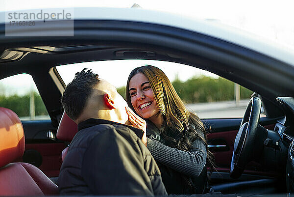 Freundin lächelt  während sie ihren Freund im Auto sitzend ansieht
