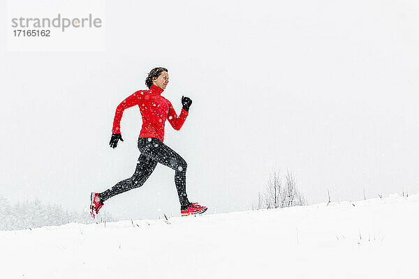 Young female athlete running on snow during winter