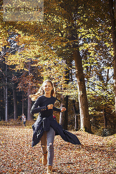 Smiling girl running in forest during autumn