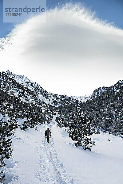 Male skier at mountain covered with snow against cloudy sky