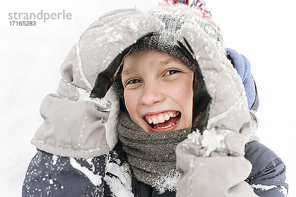 Nahaufnahme eines fröhlichen Jungen  der mit Schnee spielt