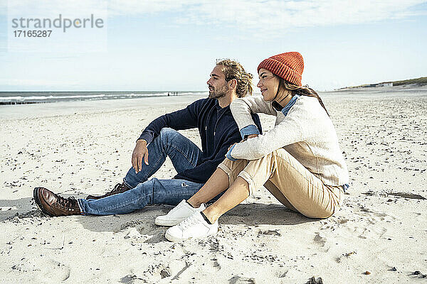 Junges Paar sitzt zusammen am Strand