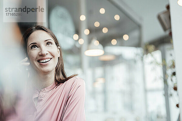 Geschäftsfrau lächelt  während sie in einem Café mit ihrem Smartphone telefoniert