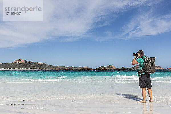 Mann mit Rucksack beim Fotografieren der türkisfarbenen Bucht  Westaustralien