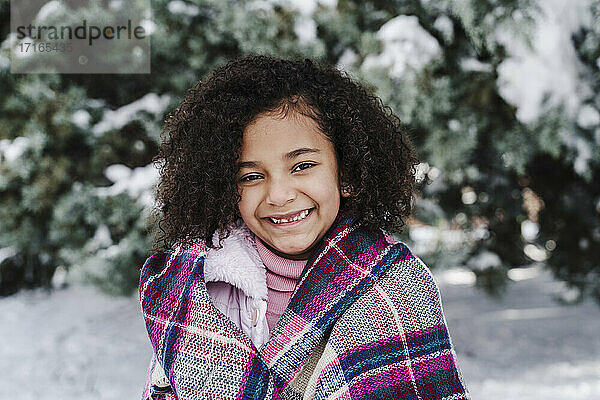 Lächelndes süßes Mädchen mit Schal im Park im Winter