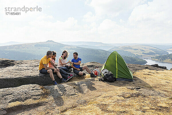 Männliche und weibliche Wanderfreunde beim Zelten auf einem Berggipfel im Urlaub
