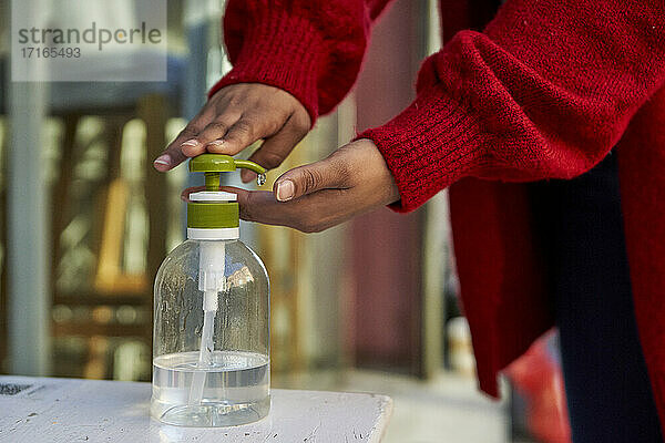 Woman using hand sanitizer while standing outdoors during COVID-19