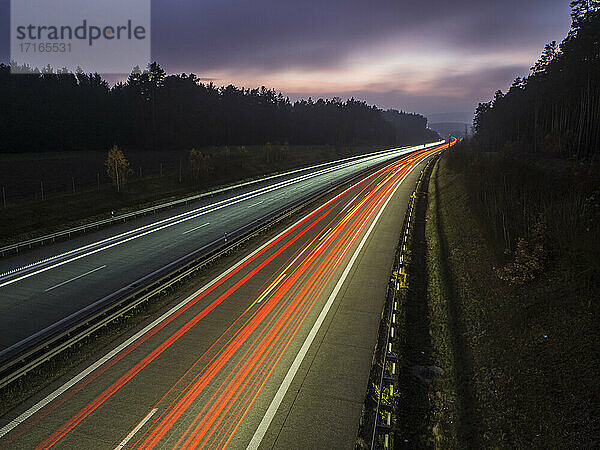 Light trails on motorway against sky during dusk