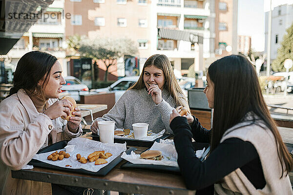 Weibliche Freunde beim schnellen Essen in einem Restaurant im Freien