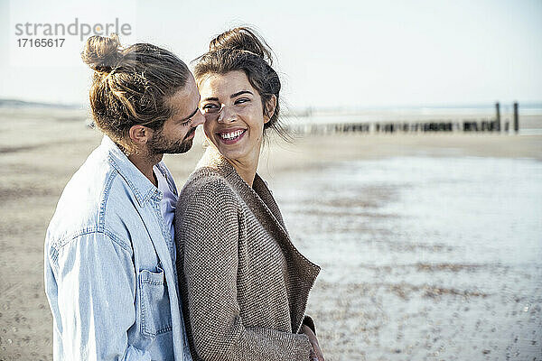 Lächelnde Freundin schaut ihren Freund an  während sie am Strand steht
