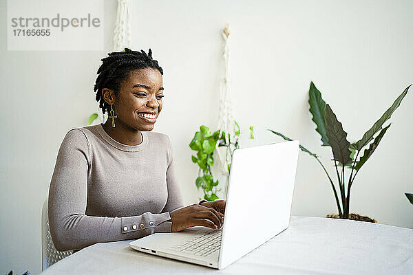 Young female entrepreneur working on laptop in living room