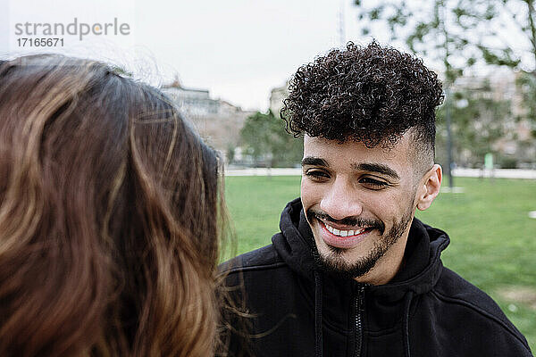 Smiling young man with female friend at public park