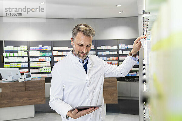 Male pharmacist doing inventory with digital tablet