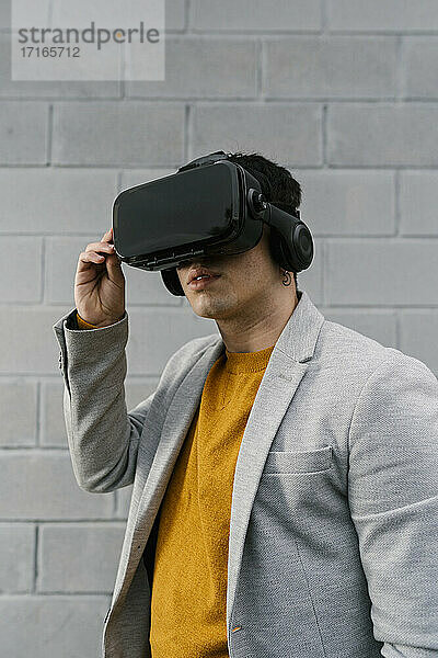 Mann mit Virtual-Reality-Headset vor einer grauen Wand
