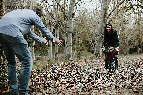 Eltern lehren Kleinkind Sohn Spaziergang im Wald im Herbst