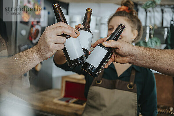 Chefs toasting beer bottles while standing in kitchen