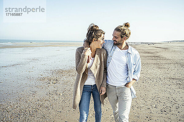 Junges lächelndes Paar  das sich beim Strandspaziergang am Wochenende ansieht