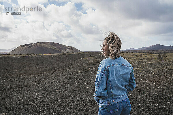 Lächelnder Tourist  der die Aussicht betrachtet  während er am Vulkan El Cuervo steht  Lanzarote  Spanien