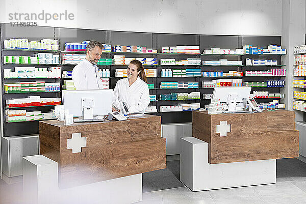 Male and female pharmacists working at pharmacy checkout