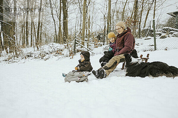 Frauen mit Töchtern und Border Collie verbringen das Wochenende zusammen im Winter im Schnee