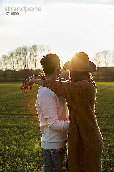 Couple embracing on green land during sunset