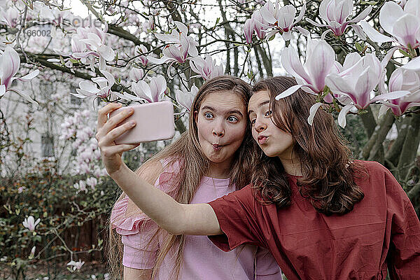 Female friends puckering while taking selfie through smart phone