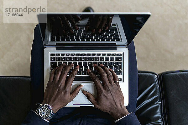 Männlicher Berufstätiger  der einen Laptop benutzt  während er im Hotel sitzt