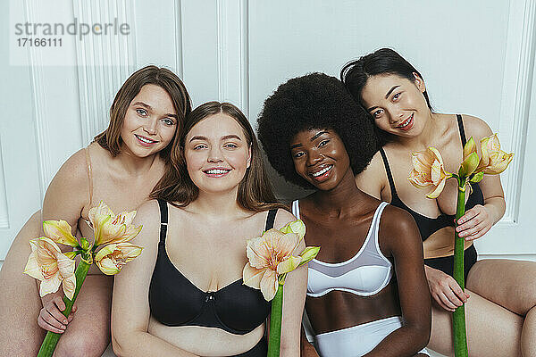 Schöne multi-ethnische Gruppe von Mode-Modelle in Dessous mit Blumen gegen weiße Wand
