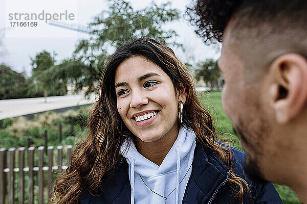 Smiling teenage girl with male friend at public park