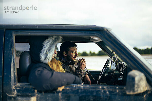 Junger Mann benutzt CB-Funk  während er im Winter mit einer Freundin im Auto unterwegs ist