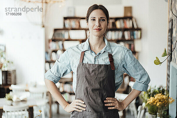 Selbstbewusste Managerin mit Hand in der Hüfte in einem Café stehend